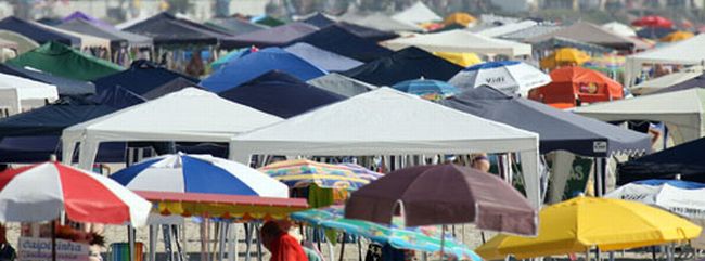 Sol forte obriga veranistas a se abrigarem em guarda-sóis e tendas na areia | Hedeson Alves/Gazeta do Povo