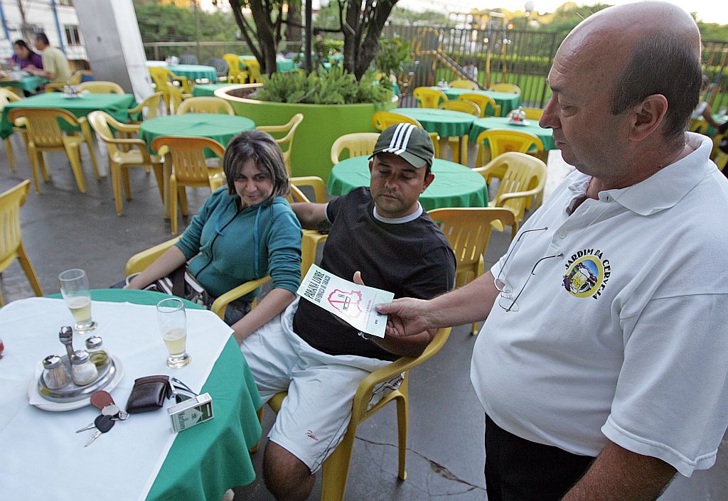 O modo como a lei está sendo aplicada é errado e não vai dar certo. Fere o direito de ir e vir. Juarez Lima, turista carioca (de preto), que teve de fumar no estacionamento de um restaurante em Foz do Iguaçu | Christian Rizzi/Gazeta do Povo