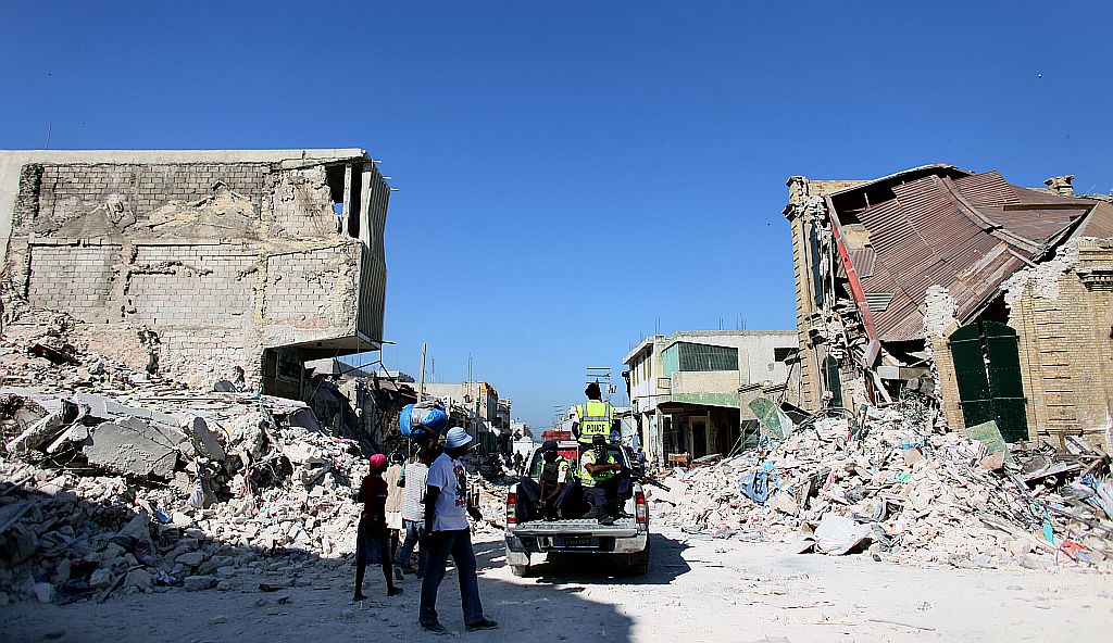 Patrulha haitiana passa por rua destruída em Porto Príncipe, enquanto governo tenta reconstruir os prédios públicos e retomar serviços básicos: dinheiro internacional será destinado à moradia, saúde e segurança | Thomas Coex/AFP
