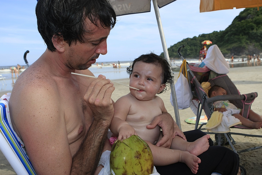 Blindada contra o calor - Maria Flor é bem cuidada pelo pai Ednaldo Barreira: corpo seco com a toalha depois do banho de mar e água de coco para matar o calor | Fotos: Antonio Costa / Gazeta do Povo