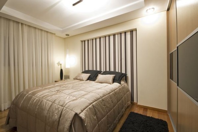 O quarto projetado pelo escritório Arqtríade foi decorado com papel de parede com listras finas, aplicado na cabeceira da cama |