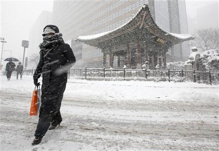Mulher atravessa rua durante neve pesada em Seul no dia 4 de janeiro. O frio e a neve golpearam o nordeste da Ásia nesta segunda-feira, afetando especialmente os transportes no norte da China e na Coreia do Sul. | Reuters