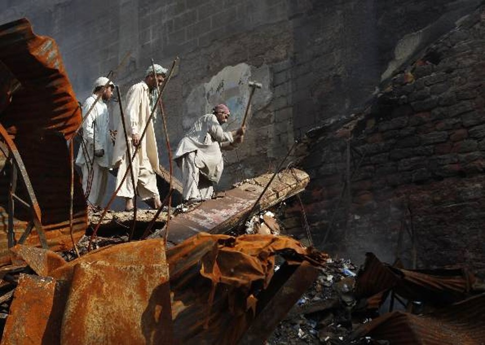 Homem tenta recuperar pertences em meio a destroços de lojas com explosão de carro-bomba em Karachi | Reuters
