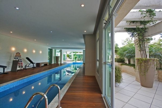 Piscina coberta foi integrada à área externa para contemplação do paisagismo | 