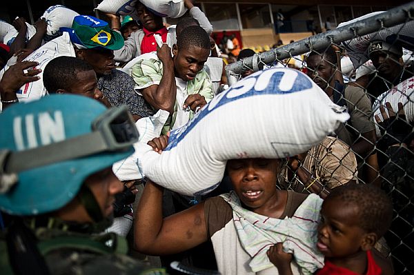 Os alimentos estão sendo entregues somente às mulheres, mas o programa incentiva os homens a esperá-las do lado de fora, por motivo de segurança | Fred Dufour/AFP
