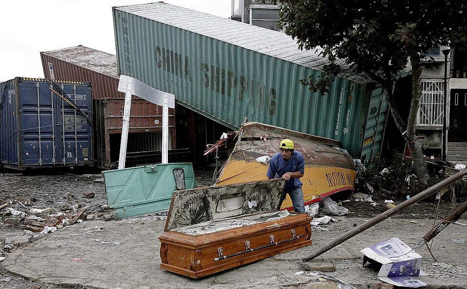 Homem examina caixão em área portuária no Chile | Reuters