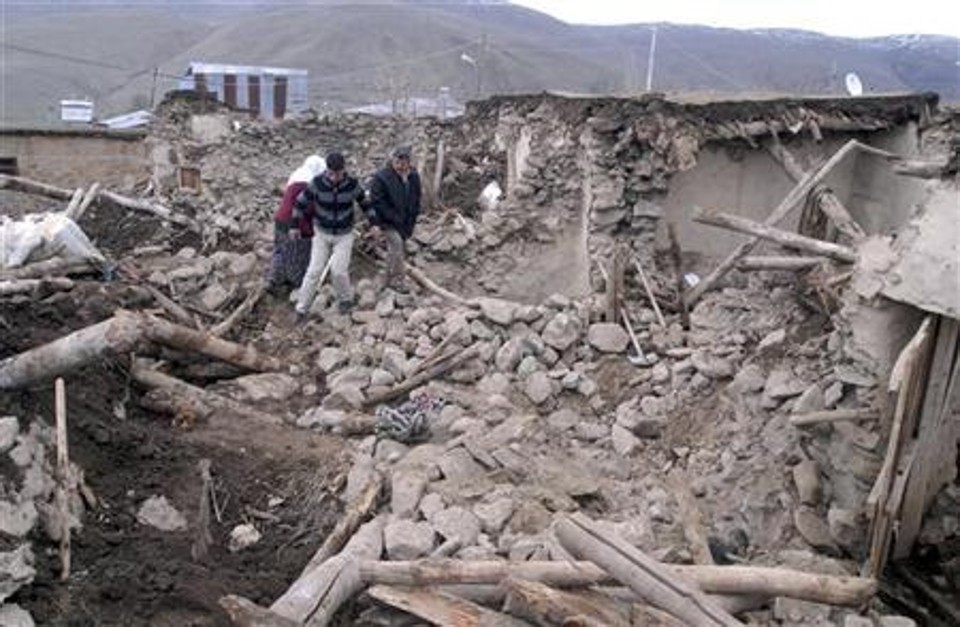 Pessoas caminham em meio a destroços de uma casa destruída por terremoto em Elazig, na Turquia | Reuters
