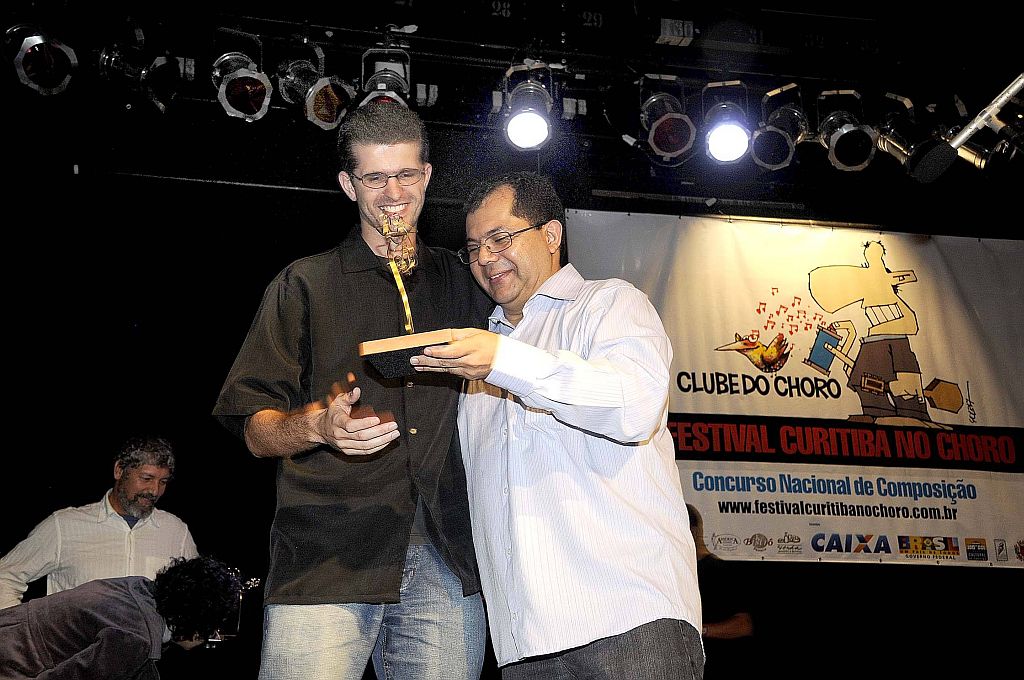 O músico Daniel Migliavacca (esquerda), recebendo o prêmio de melhor instrumentista de choro do jurado e também músico Nailor Proveta | Kraw Penas/Divulgação