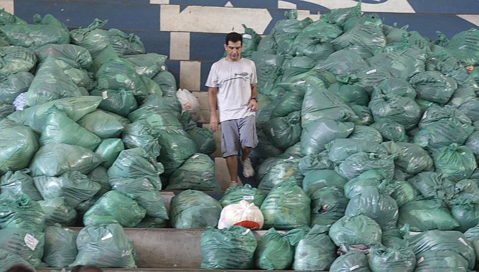 Homem caminha entre pilhas de doações arrecadadas em benefício das vítimas das chuvas no Rio de Janeiro | Bruno Domingos / Reuters