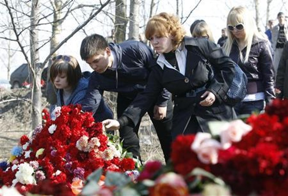 Pessoas deixam flores no local do acidente do avião que transportava membros do governo polonês, próximo ao aeroporto de Smolensk, na Rússia | Reuters