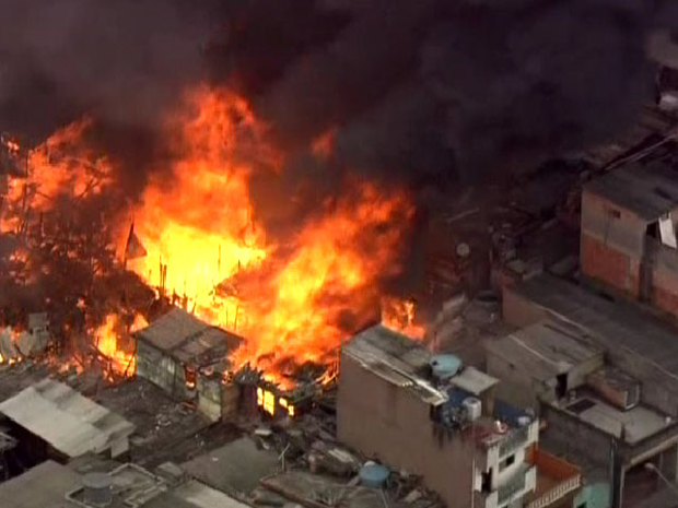 O fogo teria começado em dois barracos e se espalhado rapidamente. Dez equipes de bombeiros combatem o incêncio | Reprodução / TV Globo