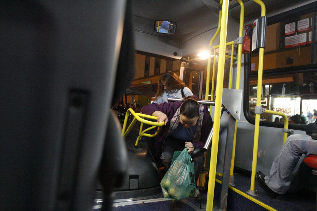 Passageira passa por baixo da catraca para não pagar passagem. Por vandalismo ou necessidade, em algumas linhas esse tipo de comportamento é rotina | Daniel Derevecki/Gazeta do Povo