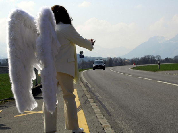 Ator vestido de anjo pede para motoristas diminuírem velocidade em estrada na Suíça. | Divulgação