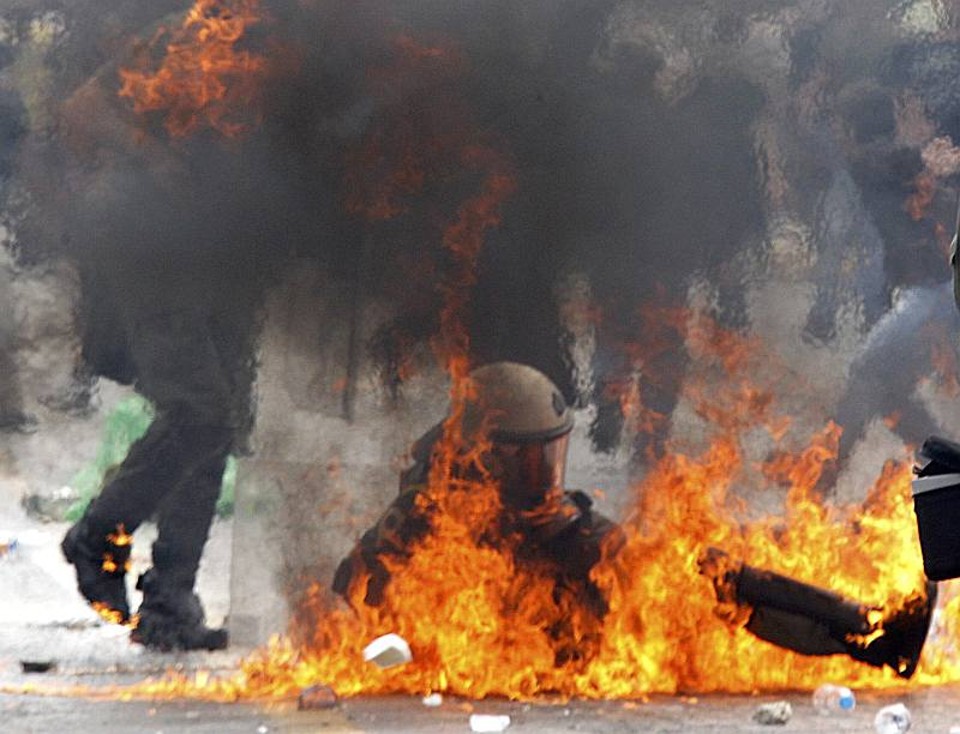 Policial cai após ser atingido por um coquetel molotov durante protesto em Atenas, na Grécia | Pascal Rossignol / Reuters