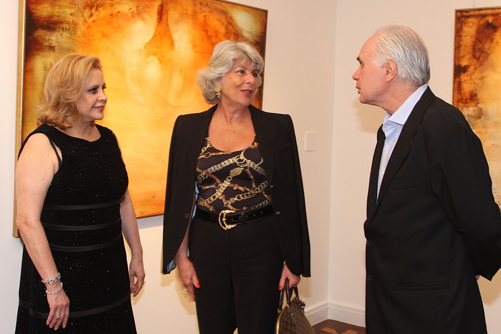 Neuza Mattos Leão (à esq.) e a ex-primeira-dama Maristela Requião com o artista plástico Carlos Araujo, no vernissage da exposição Bíblia Citações, na Simões de Assis Galeria de Arte. A mostra, inaugurada no último dia 4, fica em cartaz até 24 de maio | Mauro Campos