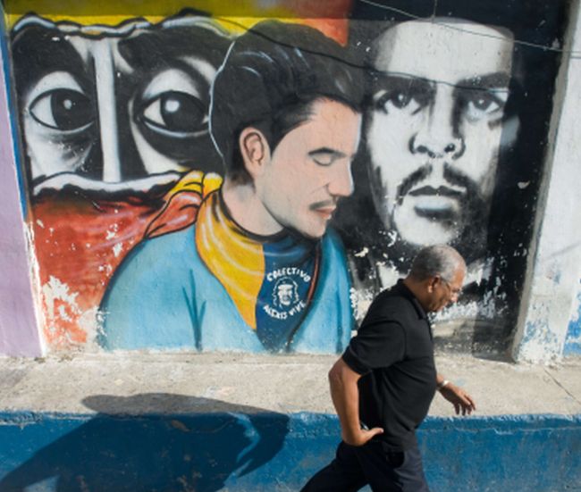 Homem
passa por desenho de
Che Guevara
sob os olhos
de Simón Bolívar, em Caracas: ídolos do governo bolivarianista | Miguel Gutierrez/AFP