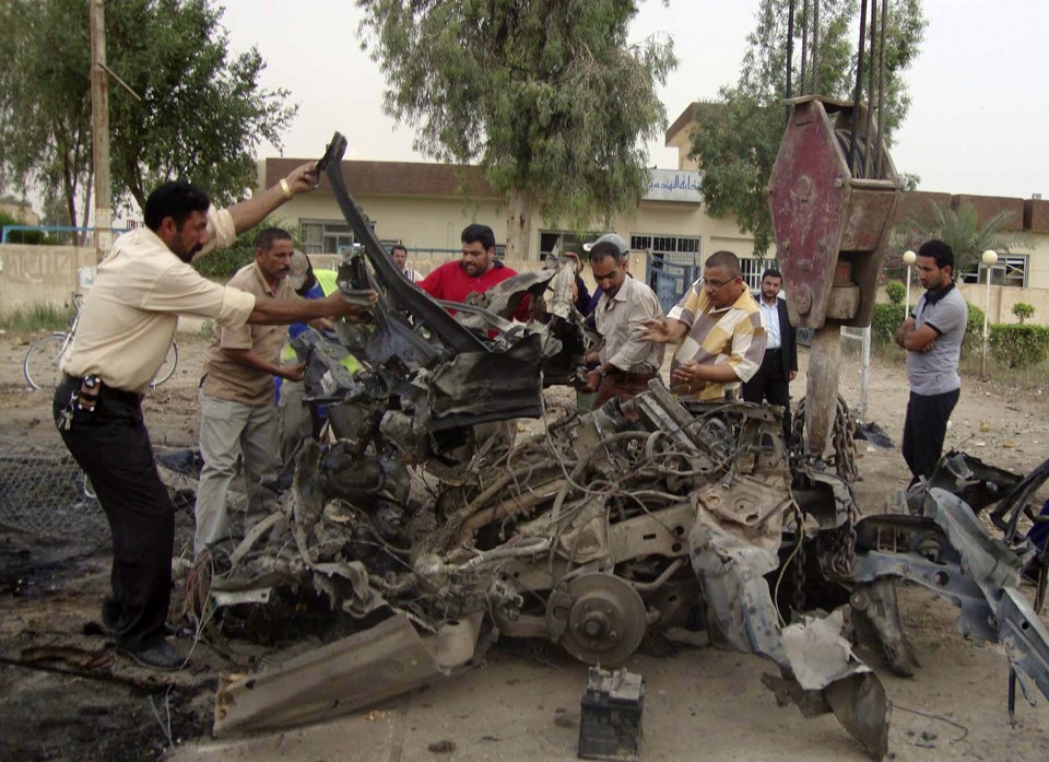 Moradores tentam remover pedaços de um carro-bomba que explodiu na cidade de Hillah. O ataque matou 35 pessoas e deixou outras 136 feridas. | REUTERS/Mushtaq Muhammed