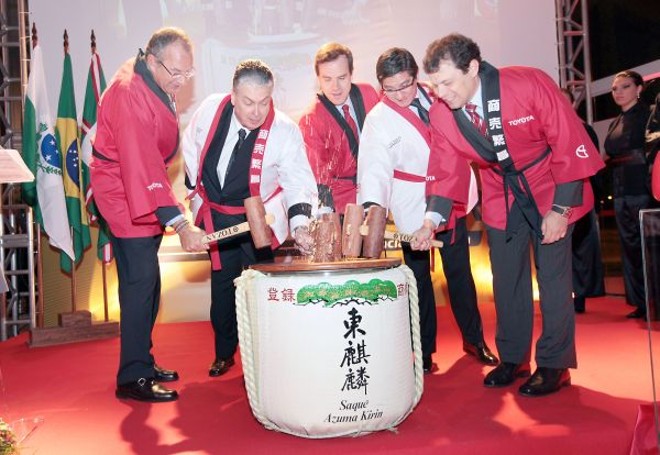 O diretor superintendente da concessionária Toyota Sulpar, Gastão Döring (de branco, à esq.), o vice-presidente sênior da Toyota Mercosul, Luiz Carlos Andrade Júnior (à esq.); o diretor comercial Brasil, Frank Peter Gundlach; o presidente do Banco Toyota, Luiz Horácio Montenegro (também de branco); e o presidente da Associação Brasileira dos Distribuidores Toyota, Riguel Chieppe (à dir.) participam do Kágamiwari (cerimônia do saquê) na inauguração da nova loja do grupo, no Alto da XV | 