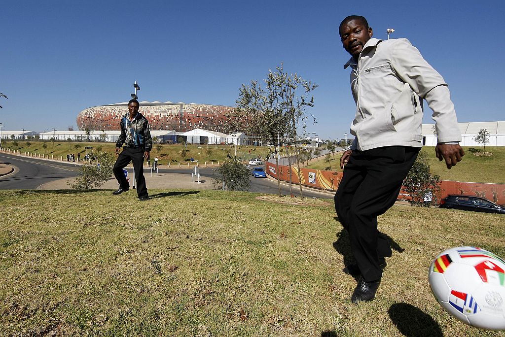 Sul-africanos brincam com a bola em frente ao pomposo Soccer City, estádio do jogo de abertura, amanhã | Valterci Santos/Gazeta do Povo enviado especial