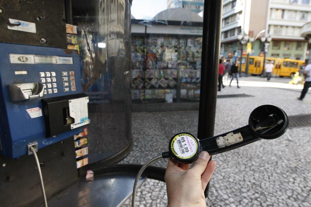 Orelhão estragado no calçadão da Rua XV de Novembro: até adesivo de propaganda foi colado no telefone | Marcelo Elias/Gazeta do Povo