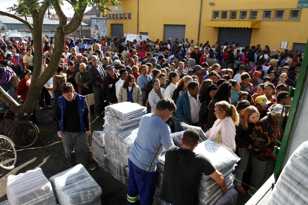 Entrega de cobertores no Parolin, em Curitiba: famílias tiveram de esperar discursos de políticos para receber as doações | Daniel Derevecki/ Gazeta do Povo