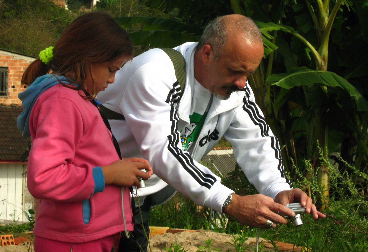 O fotógrafo Sílvio Ribeiro orienta a aluna Maria Helena, de 10 anos | Diego Linke/Divulgação