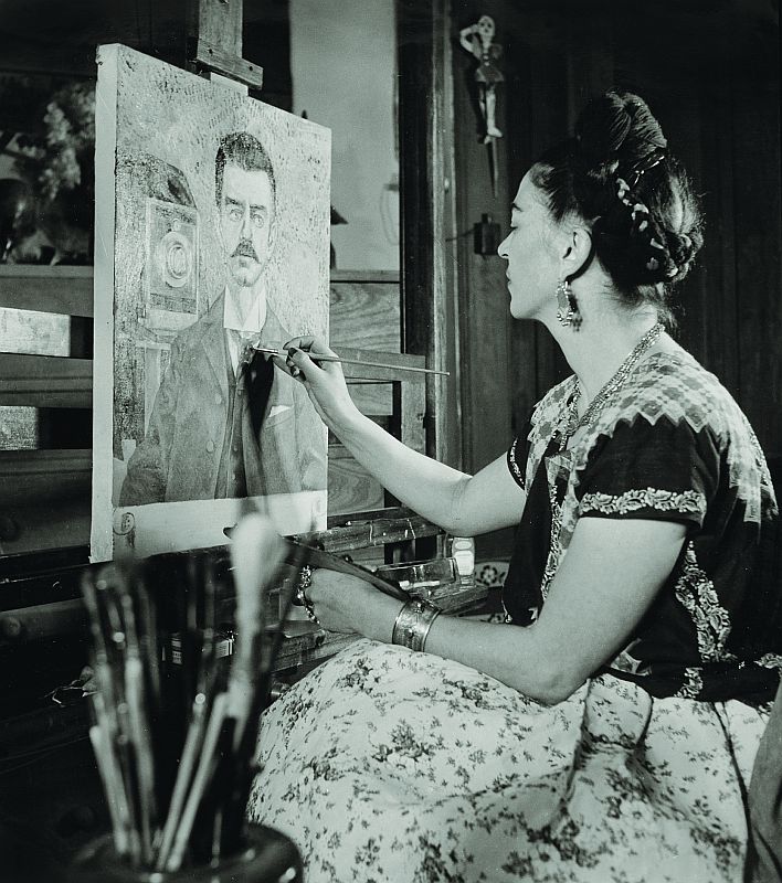 Frida Kahlo pintando o retrato de seu pai, em 1951, o fotógrafo Guillermo Kahlo, em foto de Gisele Freund. Nas obras de pai e filha, havia uma complexa relação entre a fotografia e a pintura | D.R.© 2010 Banco de México en su carácter de Fiduciario en el Fideicomiso relativo a los Museos Die