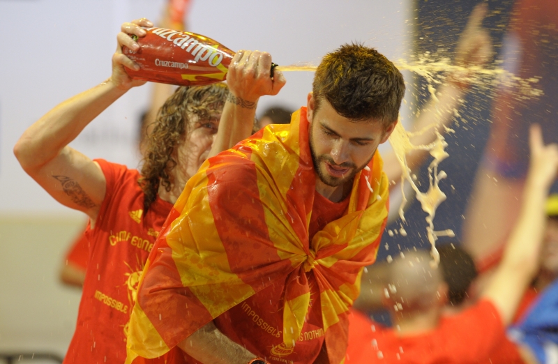 O catalão Puyol derrama champanhe no colega de time e conterrâneo Piqué, devidamente enrolado na bandeira catalã: boa participação dos jogadores da região autônoma fez surgir esperança de unificação nacional pelo esporte | Miguel Riopa/AFP