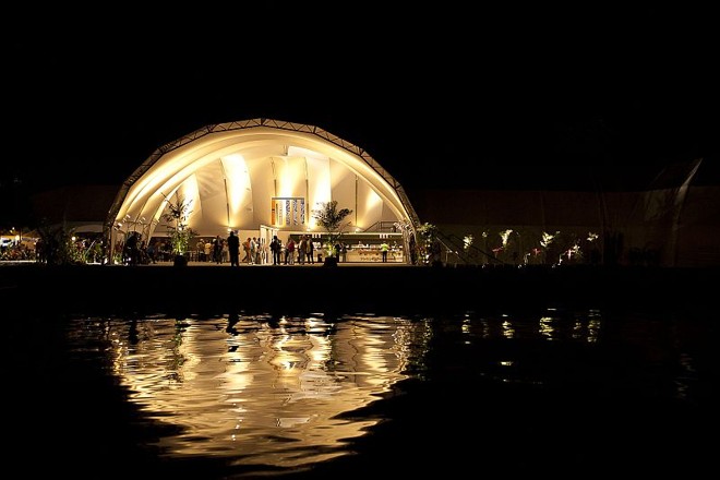 Festa muda a paisagem de Paraty - A Tenda dos Autores, refletida no Rio Pequerê-açú, é onde os autores participam das mesas. Uma segunda tenda, a do telão, montada do outro lado do rio ao lado da Praça da Matriz, no Centro Histórico, transmite as discussões ao vivo. A estrutura da Flip se completa com um café instalado na saída da tenda principal, uma livraria oficial (a Livraria da Vila), a loja de lembranças da festa (com canecas e bolsas disputadas a tapa) e o espaço para as sessões de autógrafos. Mesmo que você não consiga comprar ingressos para nenhuma das tendas, ainda é possível assistir às mesas nas redondezas da praça, de graça |