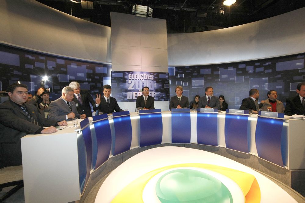 Os candidatos, sentados à bancada: Robinson de Paula (PRTB), Paulo Salamuni (PV), Beto Richa (PSDB), o mediador das discussões (Fabrício Binder), Luiz Felipe Bergmann (PSol), Osmar Dias (PDT), Avanílson Araújo (PSTU) e Amadeu da Luz Ferreira (PCB). Muita gente, poucas ideias para o futuro do estado. | Pedro Serápio / Gazeta do Povo