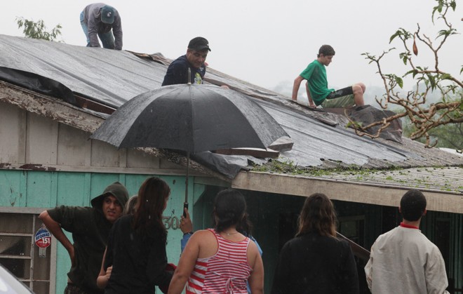 Famílias tentam reparar as telhas danificadas. |