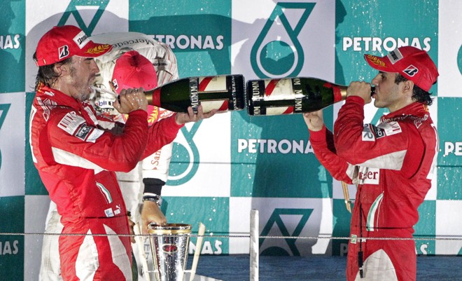 Pilotos da Ferrari Fernando Alonso e Felipe Massa comemoram no pódio o primeiro e o terceiro lugares no GP da Coreia do Sul. | REUTERS/Bazuki Muhammad