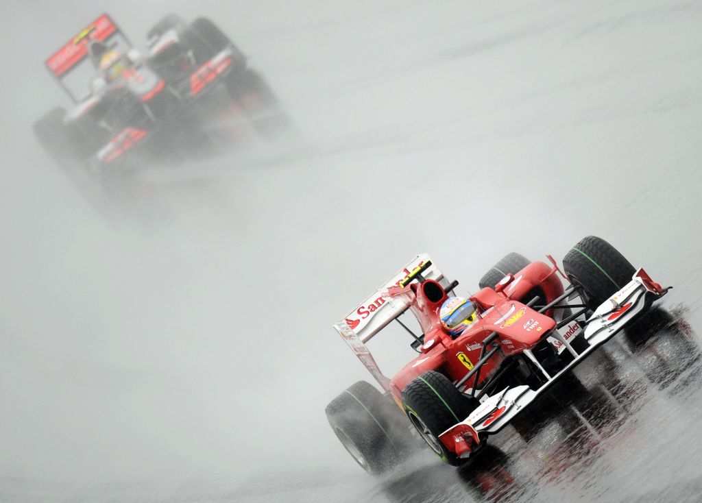 Debaixo de chuva no circuito de Yeongam, a Ferrari do espanhol Fernando Alonso segue para a vitória à frente da McLaren do inglês Lewis Hamilton. Ambos seguem na disputa pelo título | Peter Parks/AFP