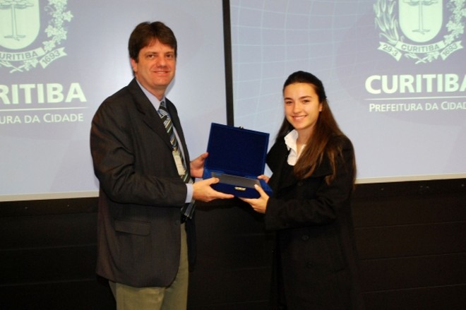 O conselheiro do Instituto Curitiba de Informática (ICI) Luciano Scandelari entrega placa à Illana Küster, filha do ex-procurador-geral do município Eraldo Küster na homenagem póstuma prestada aos integrantes do seu Conselho de Administração Leopoldo Ehrlich e Eraldo Küster, falecidos, respectivamente, em junho e julho deste ano | 