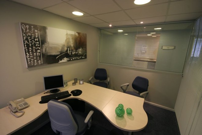 A meia parede em vidro permite visibilidade das ilhas de trabalho |