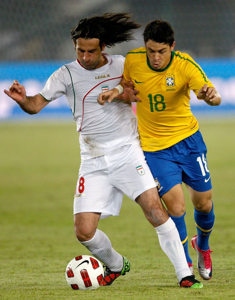 Giuliano disputa jogada com iraniano. Meia paranaense debutou com a camisa da seleção principal | Marwan Maamani/AFP