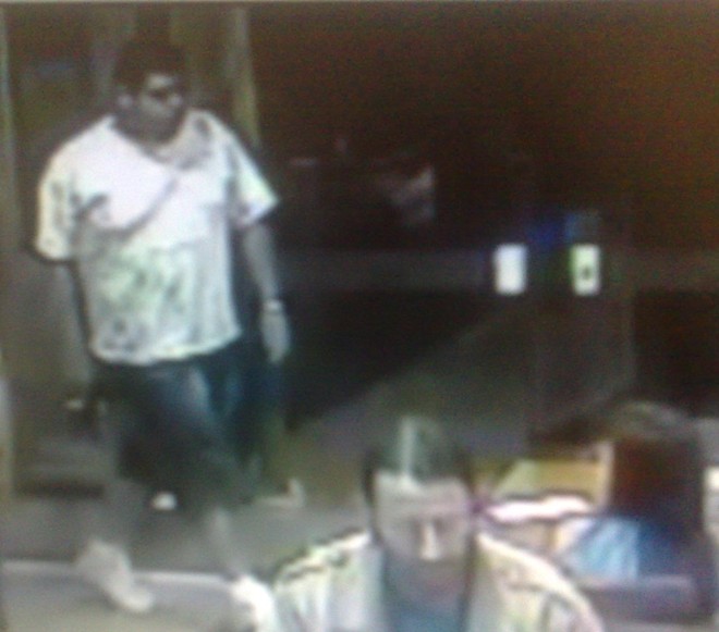 Com arma em punho, bandido vigia a porta do restaurante, durante o assalto | 