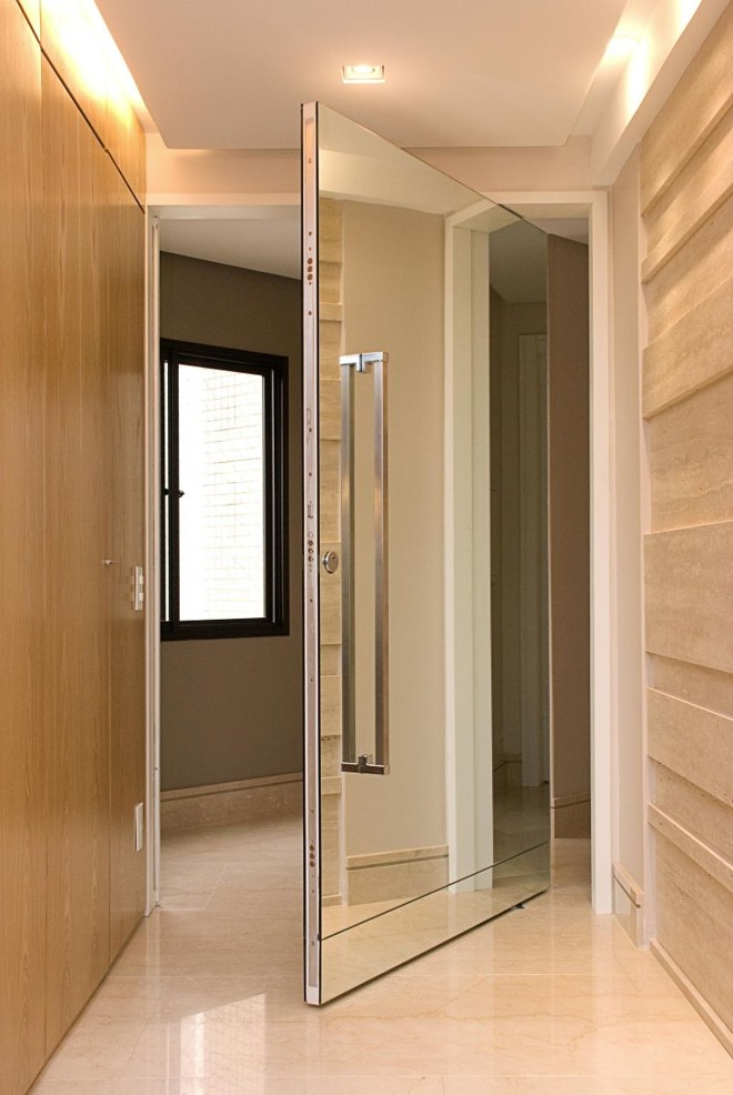 Destaque para o puxador vertical em aço inox na porta revestida de espelho, no projeto de Jorge Elmor. O espelho foi produzido pela MR Móveis | 