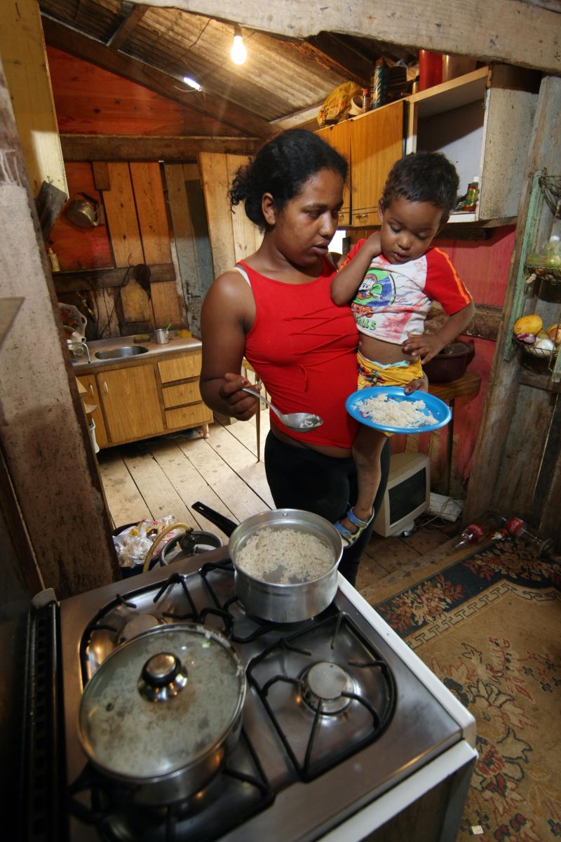 Victor no colo da mãe, Juliana: a foto não é posada. Ele realmente estava com fome e a mãe precisou alimentá-lo antes do previsto. O arroz é racionado para durar até de noite. | Albari Rosa/Gazeta do Povo