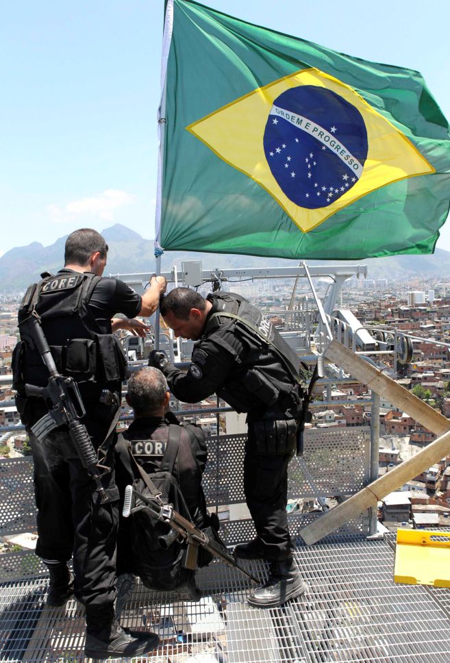 Policiais hasteiam a bandeira do Brasil como símbolo da conquista. | Sergio Moraes - Reuters