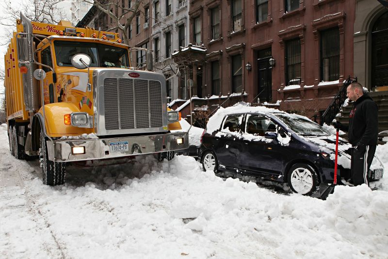 Nova-iorquino assiste caminhão tentando remover a neve de seu carro | AFP
