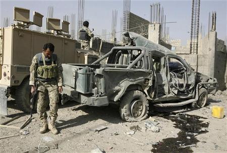 Policial afegão inspeciona carro-bomba após explosão em Candahar. Ao menos três policiais que estavam na fila de um banco morreram. 27/12/2010 | REUTERS/Ahmad Nadeem