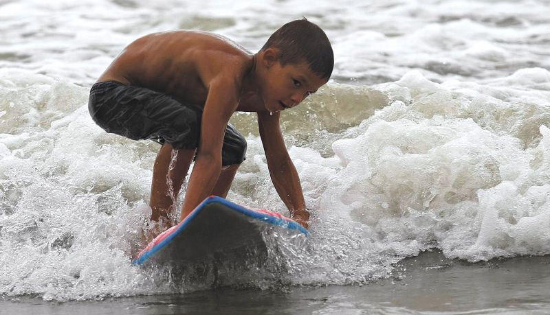 Gabriel Martins da Silva, de 6 anos, que vai para a praia surfar com o irmão Fábio, 10, e o primo Matheus, 12 | Jonathan Campos/Gazeta do Povo