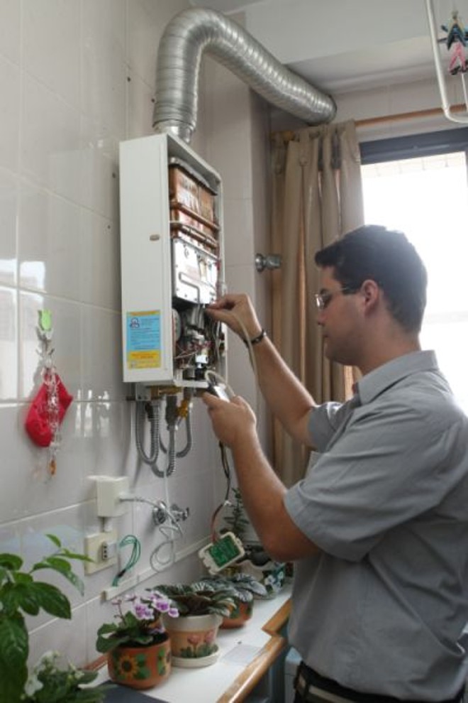 O supervisor técnico da 3B Aquecedores, Marcelo Batalha, faz a manutenção no aparelho instalado na casa do estudante Adolfo Braga | 