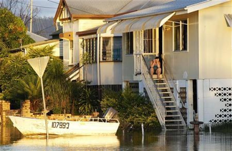 Mulher senta nas escadas de sua casa, parcialmente submersa, em Rockhampton | Reuters
