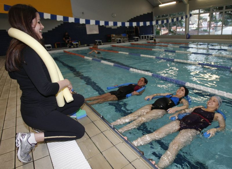A fisioterapeuta Bárbara Valente com Rosana, Gisele e Mayalu: hidroginástica para reduzir dores nas costas e preparar um melhor pós-parto | Pedro Serápio/Gazeta do Povo
