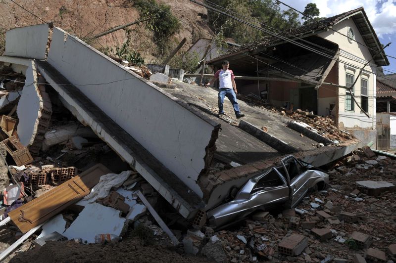 Morador caminha sobre sua casa destruída em Nova Friburgo | Mauricio Lima / AFP Photo