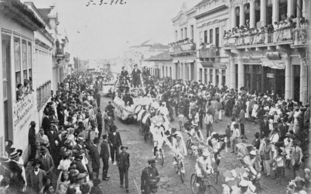 Em 1916 multidão brinca o Carnaval na Rua XV, em frente ao prédio da Associação Comercial do Paraná | Coleção Julia Wanderley/ Reprodução de Marcos Campos