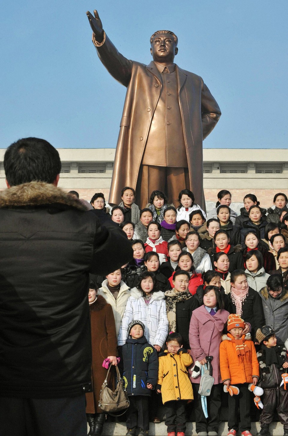 Norte-coreanos posam para foto em frente à estátua de Kim Il-Sung, fundador do país. Esta quarta é aniversário do atual líder do país, Kim Jong-il | Reuters/Kyodo