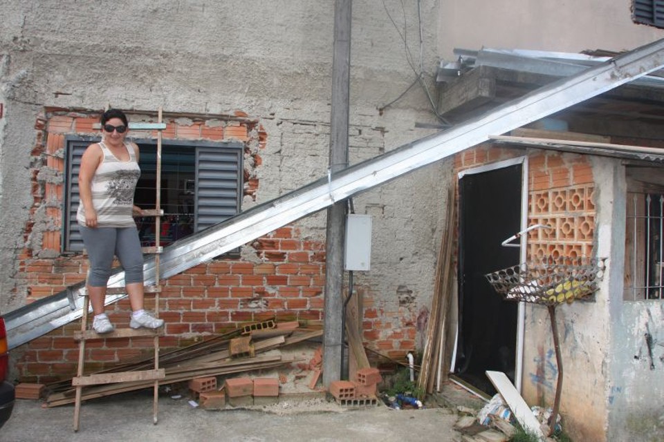 No improviso, o empreen­dedorismo- Joanita espera a regularização da área para conseguir investir sem o risco de perder tudo. Há nove anos ela mora nesse lote com dois filhos. Na parte de baixo da casa, construída no improviso, ela montou um salão de beleza e uma lojinha, ambos sem alvará. "Meu sonho é ter o terreno para poder construir direito e separar a loja do salão, e ainda poder regularizar tudo. Assim ficará muito mais organizado." | Walter Alves/Gazeta do Povo